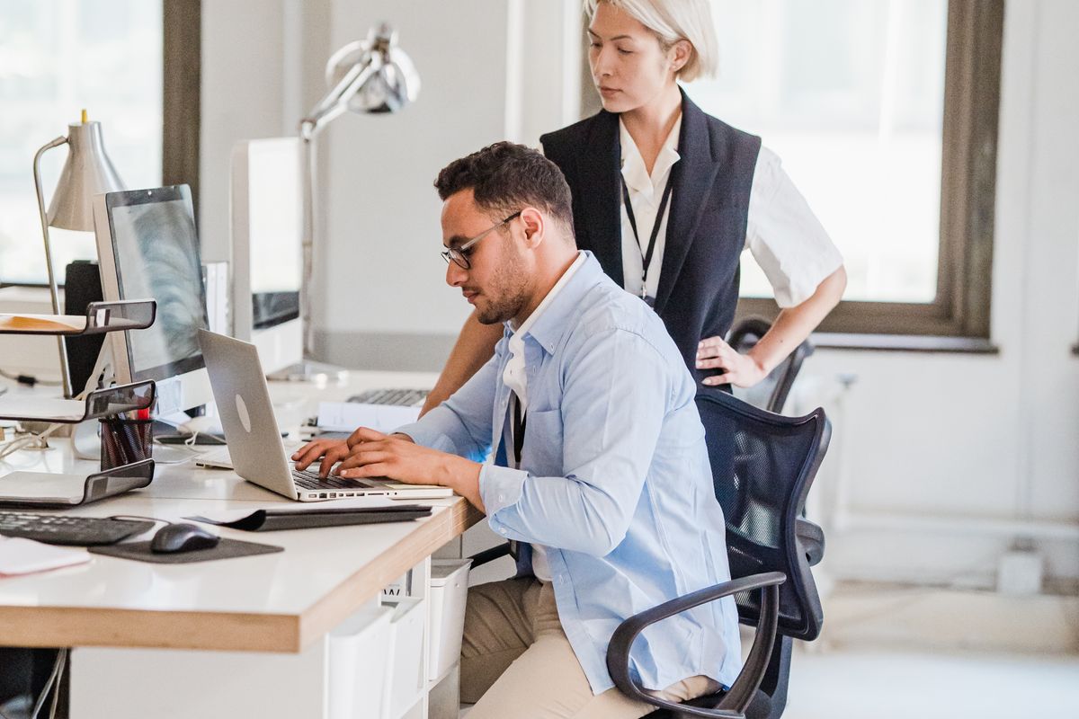 Someone working at a desk with a colleague nearby