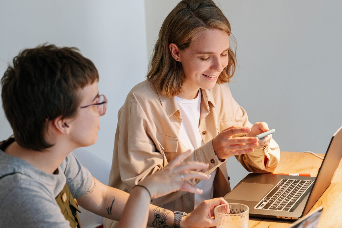 Two people talking through work at a laptop